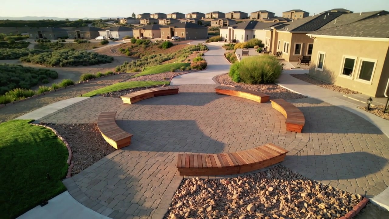 Moving drone showing circular plaza with curved benches in suburban courtyard, showing nearby homes