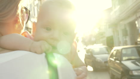 mum with baby walking outside against bright sun flare