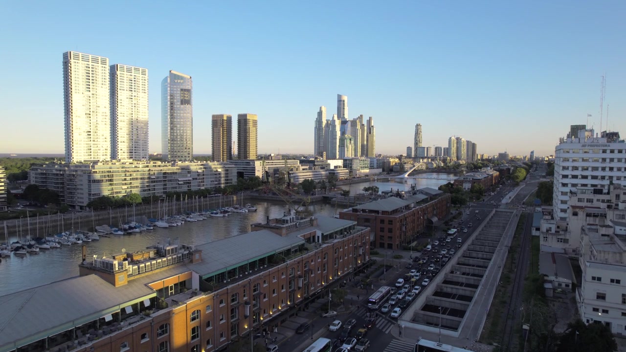 Vista aerea 4K con drone di Puerto Madero a Buenos Aires, Argentina, al tramonto. Skyline moderno riflesso sul lungomare durante l'ora d'oro nel quartiere più contemporaneo della città.