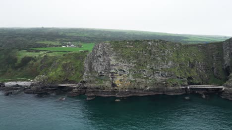 Aerial-panning-shot-of-majestic-cliffs-on-the-blue-sea-from-the-Gobbins-Cliffs-during-an-adventurous-trip-through-Northern-Ireland-on-a-calm-morning