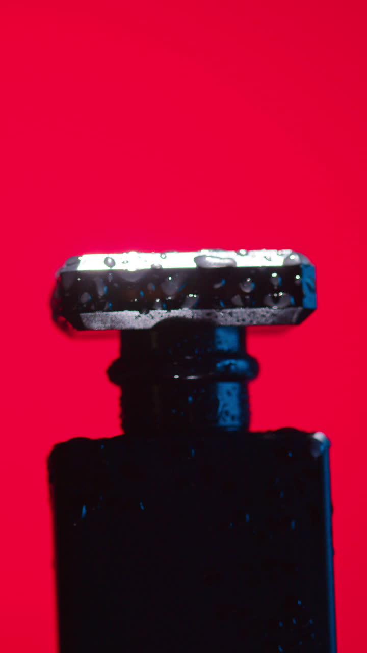primer plano de una botella de perfume negra con gotas de agua