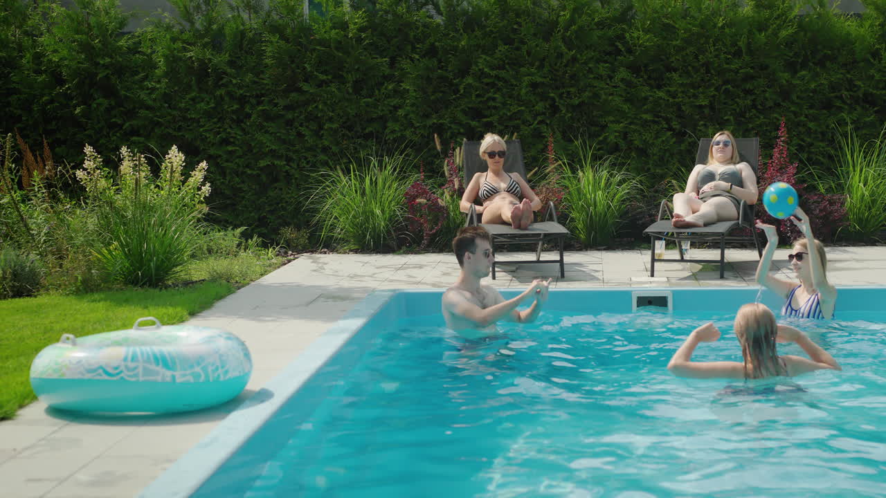 En hyggelig familie slapper af ved poolen og spiller bold. De hygger sig sammen på en varm sommerdag.