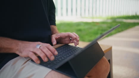 outdoors hands typing keyboard closeup. mature freelancer working tablet in park