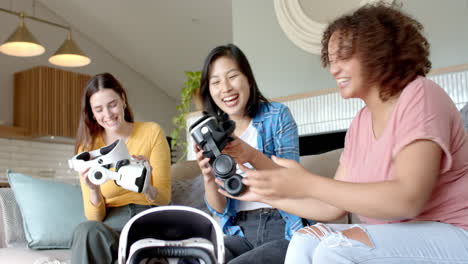using vr headsets, three diverse women friends sitting on couch enjoying virtual reality