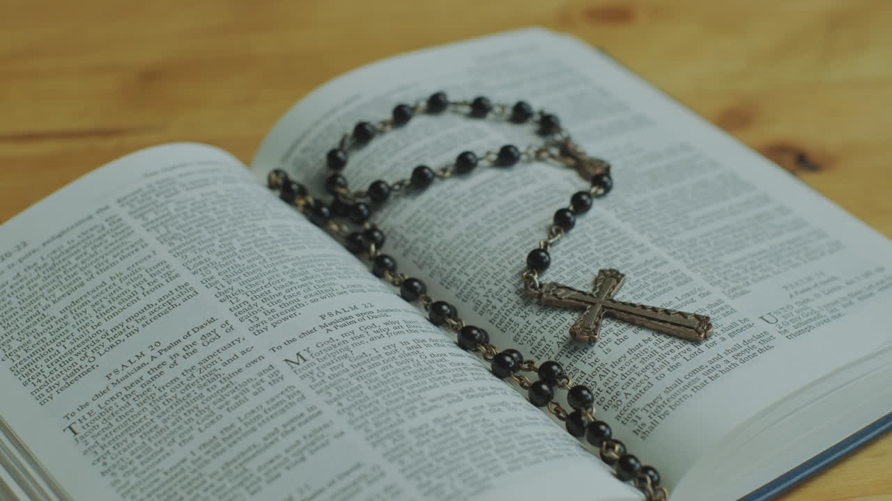 Opened Bible Book with Rosary Beads on Pages