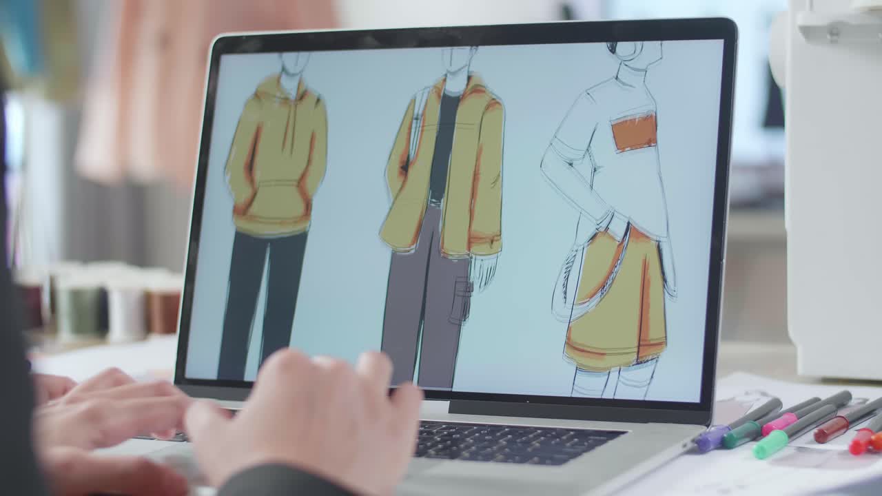 여성 디자이너의 손이 스튜디오에서 노트북으로 옷을 디자인하는 클로즈업.