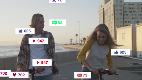 animation of social media icons on banners over happy caucasian couple on scooters by seaside