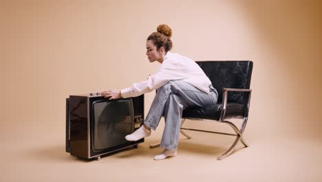 woman in chair lighting candles on retro tv set