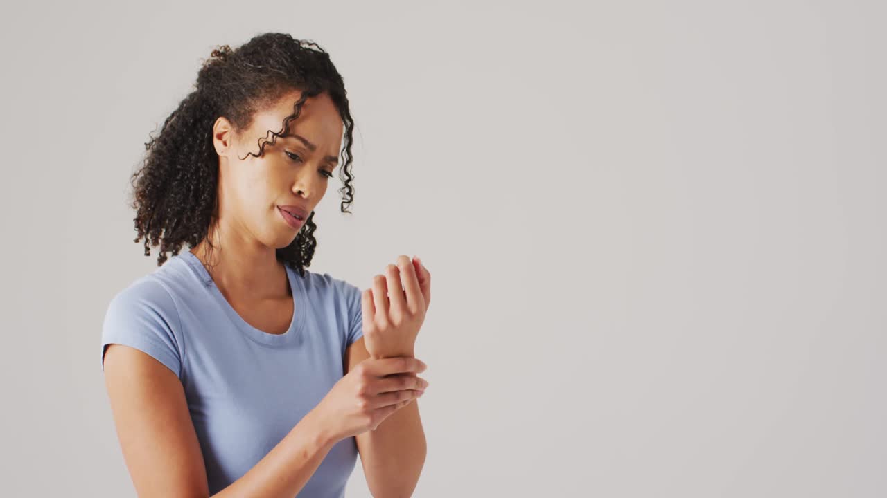 Video of biracial woman touching her wrist on white background