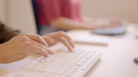 hands of a woman typing computer keyboard in a coworking