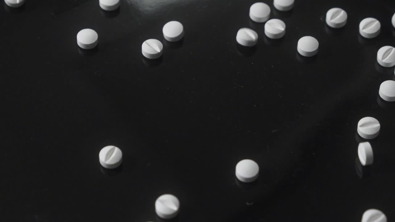 Scattered White Pills on Black Background