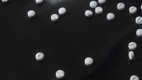 scattered white pills on black background