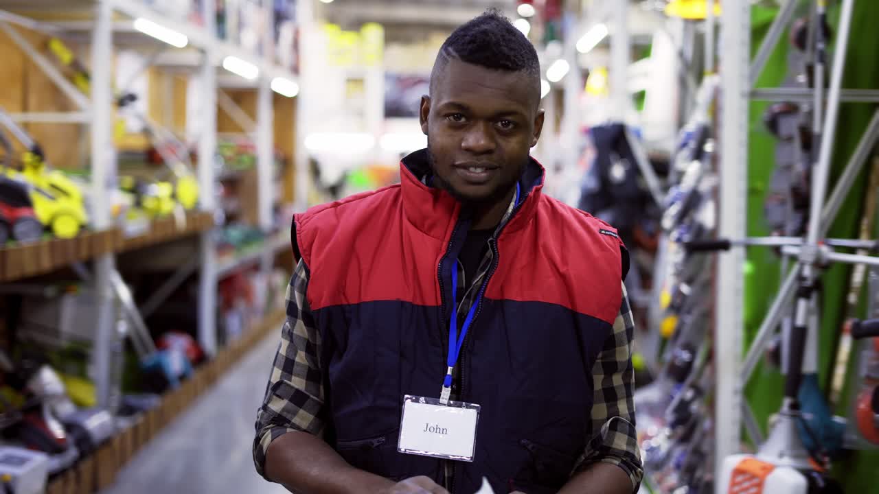 Salesman standing between rows in hardware store, looking to the camera