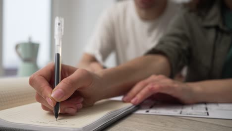 a married couple is actively discussing repairs in a new apartment or house while sitting at a table and making notes in a notebook