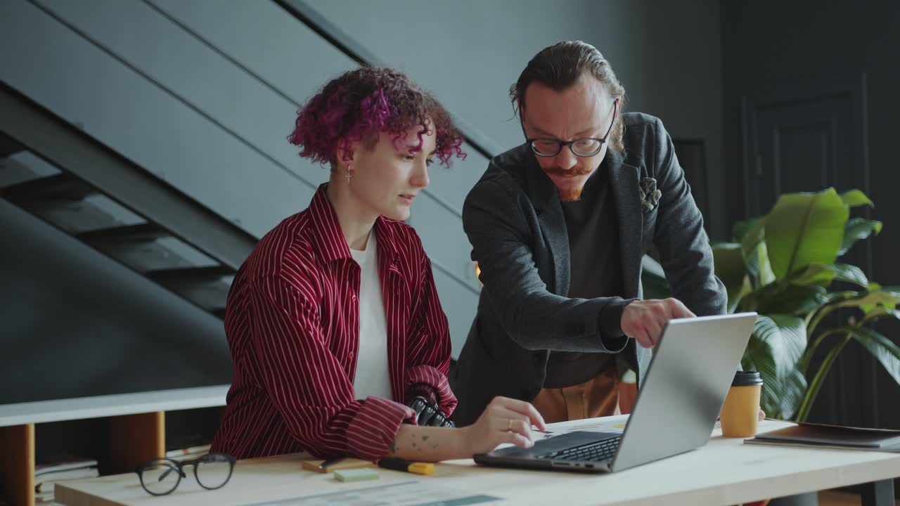 Businesswoman with Prosthetic Arm Discussing Project on Laptop with Colleague