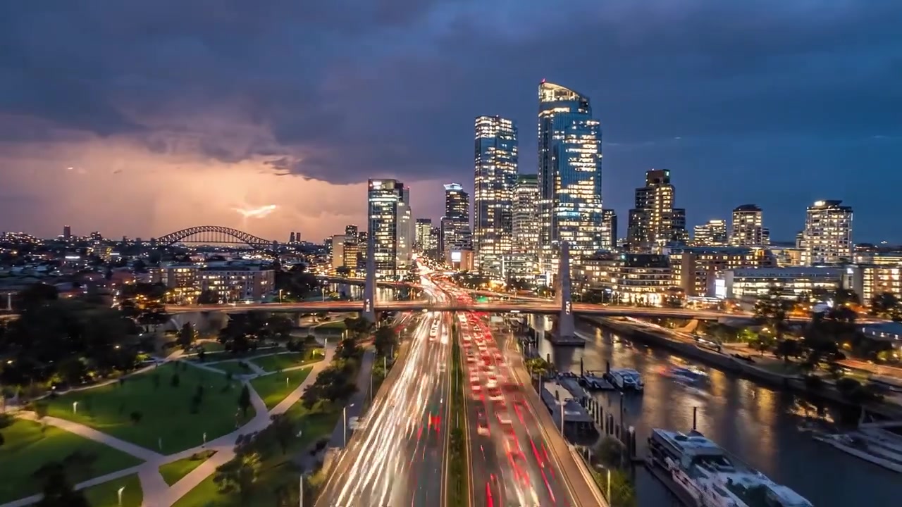 Paesaggio Urbano Notturno: Viste Mozzafiato su uno Skyline Moderno con Edifici Illuminati, Flusso di Traffico e un Ponte Scintillante Sotto un Cielo Drammatico al Tramonto