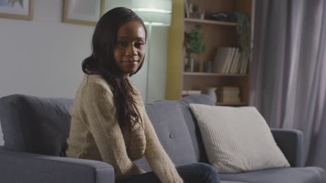 portrait of smiling young woman relaxing at home sitting on sofa 1