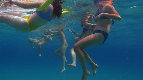 Unterwasser-Zeitlupenszene-Einer-Gruppe-Von-Freundinnen,-Die-In-Kristallklarem-Meerwasser-Mit-Poolnudeln-Schwimmen