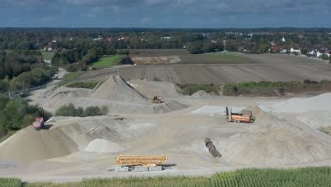 an excavator at work at a hugh sand pit in aerial view