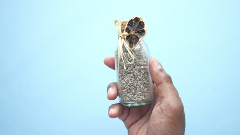 hand holding small glass bottle with dried lavender and citrus