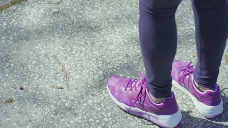 young female leg and hands tying laces on running shoe