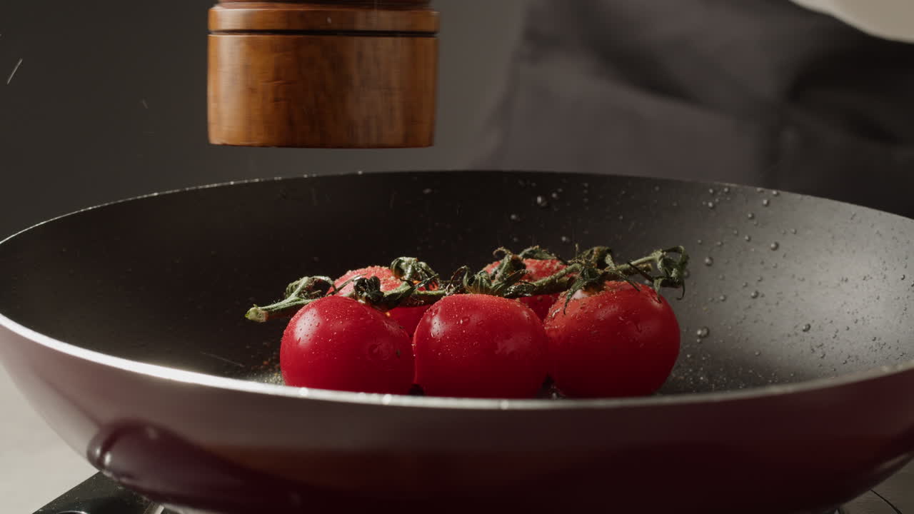 Chef Seasoning Cherry Tomatoes in a Pan