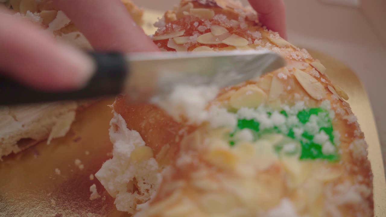 바닐라 크림으로 채워진 전통적인 스페인 크리스마스 케이크를 손으로 자르고 닫습니다.