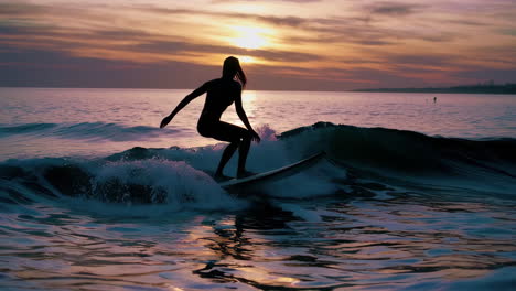 silhouette of surfer riding a wave at sunset