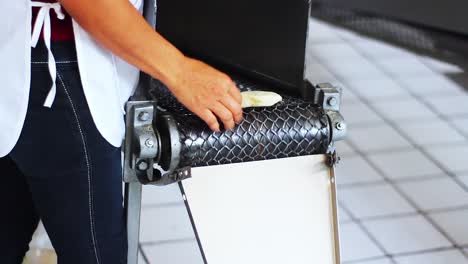 Woman-handling-fresh-corn-tortillas-from-tortilla-making-machine-traditional-mexican