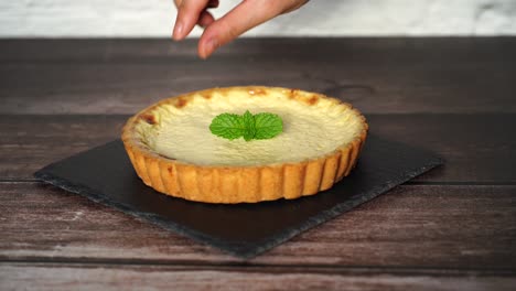 serve crème brülée tart on a wooden table then put mint leaf on it