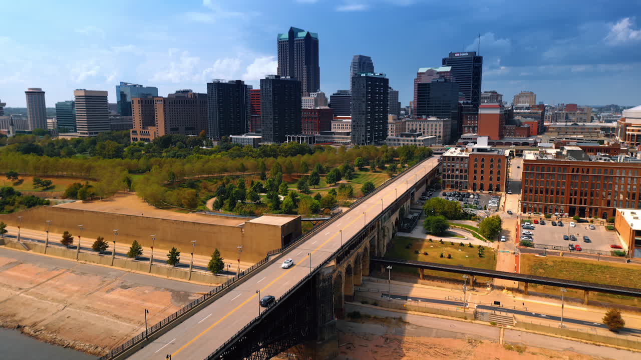 Flight above the Mississippi River approaching the waterfront with green park. Skyline of St. Louis, Missouri, USA at backdrop