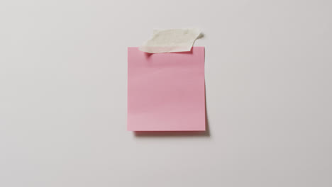 video of close up of pink memo note with copy space taped to white background