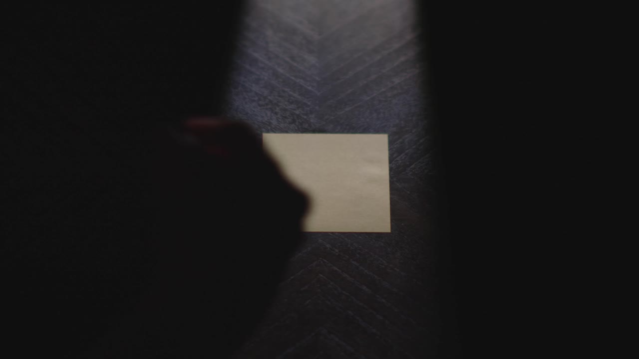 Slow motion close up footage of a hand writing out "September" on a paper note and placing it on a table. Shot in dramatic lighting for an impressive title or transition