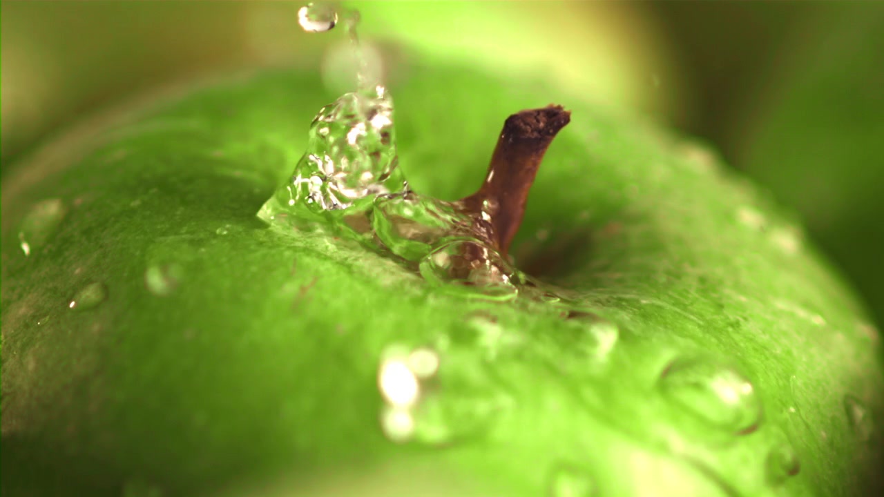 Gocce d'acqua che schizzano su una mela verde fresca al rallentatore