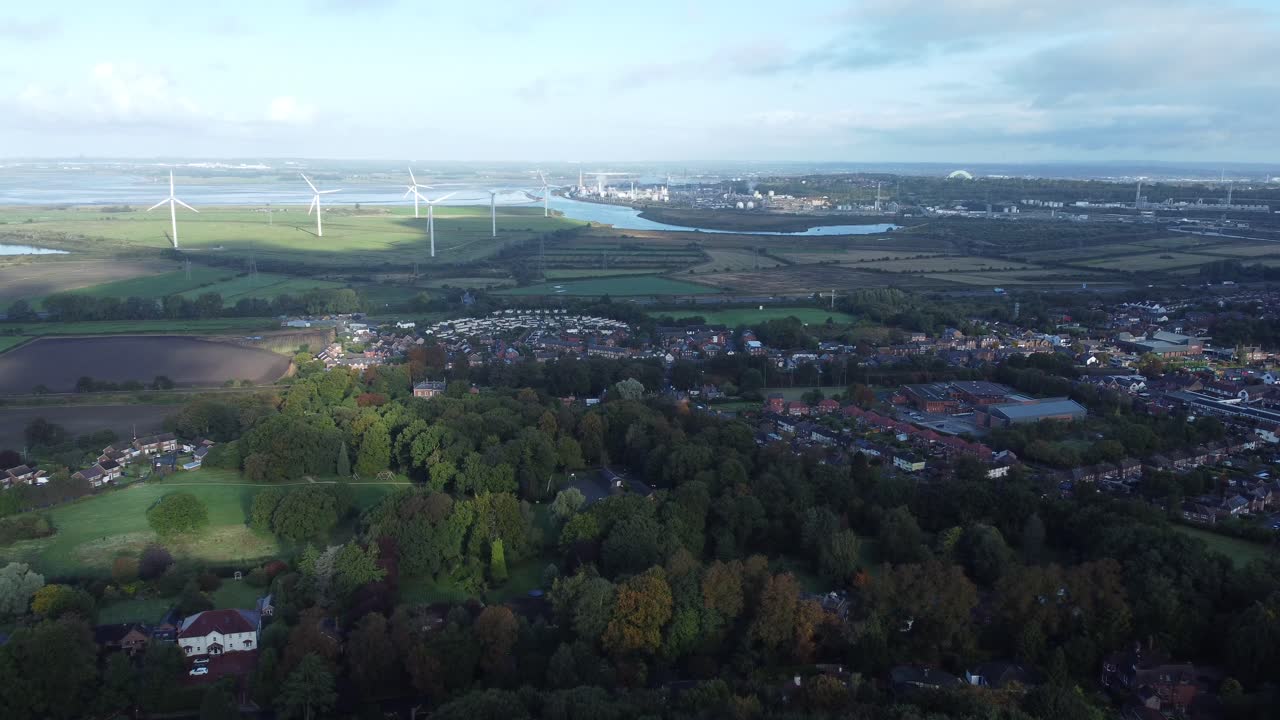 Cheshire farmland countryside wind farm turbines generating renewable green energy aerial view left panning shot