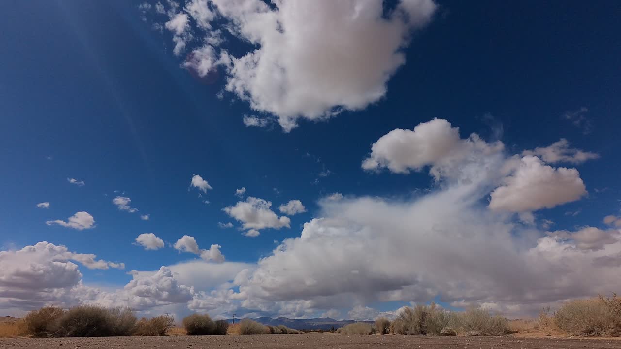 las nubes de cúmulo se forman y luego se disipan como sobre el árido paisaje del desierto de mojave - lapso de tiempo estático