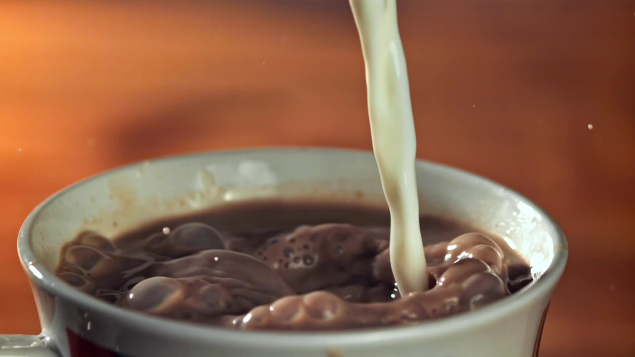 Versamento di latte al rallentatore in una tazza di cioccolata
