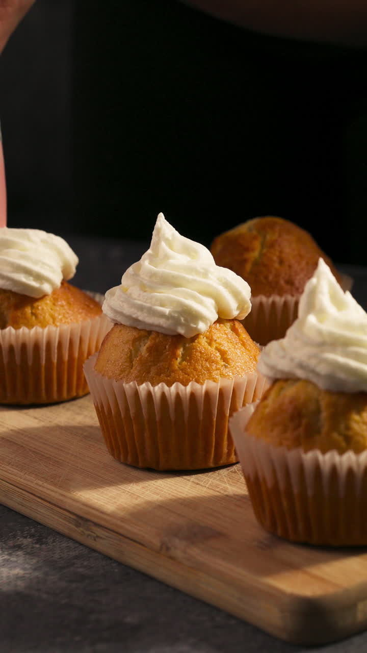Ripresa verticale di cupcake guarniti con glassa di panna montata. Primo piano