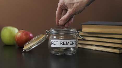 man puts coins into glass for retirement savings