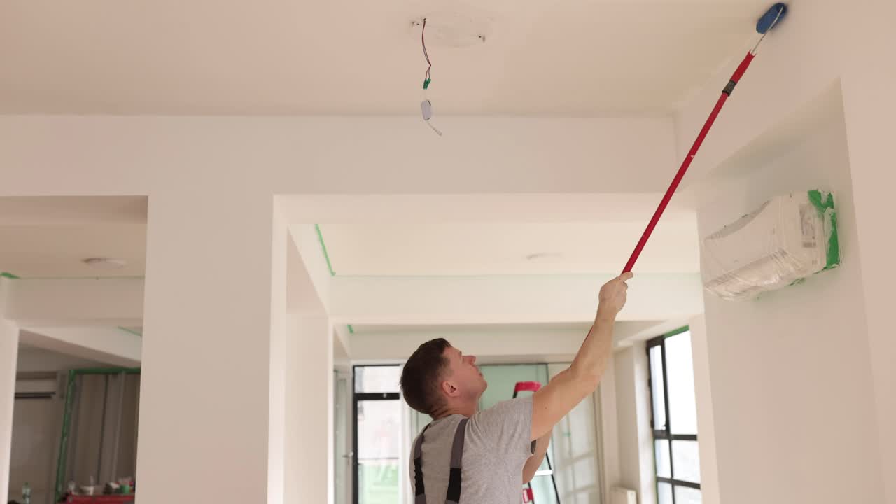 A man painting a ceiling with a roller