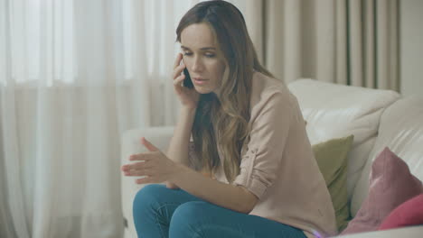 una mujer enojada hablando por teléfono en casa.