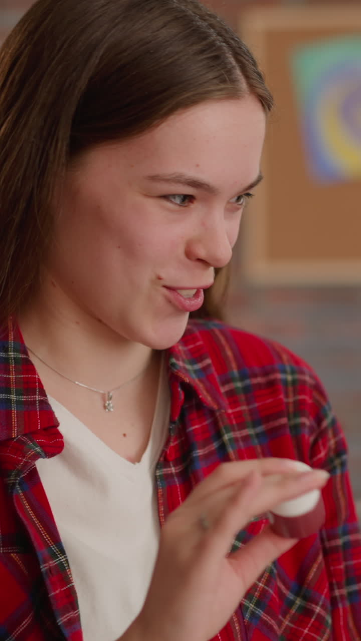 la hermana de sangre mayor divertida sacude la botella con pintura mirando a la niña en la sala de estar en cámara lenta. afición artística de la familia. suministros para el trabajo artístico