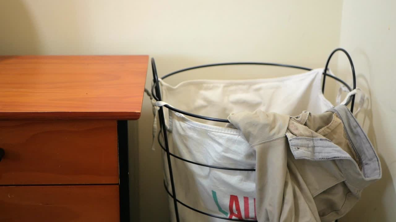 세탁 바구니에 옷을 던지고