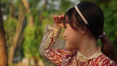 young asian girl looking into the distance in a park