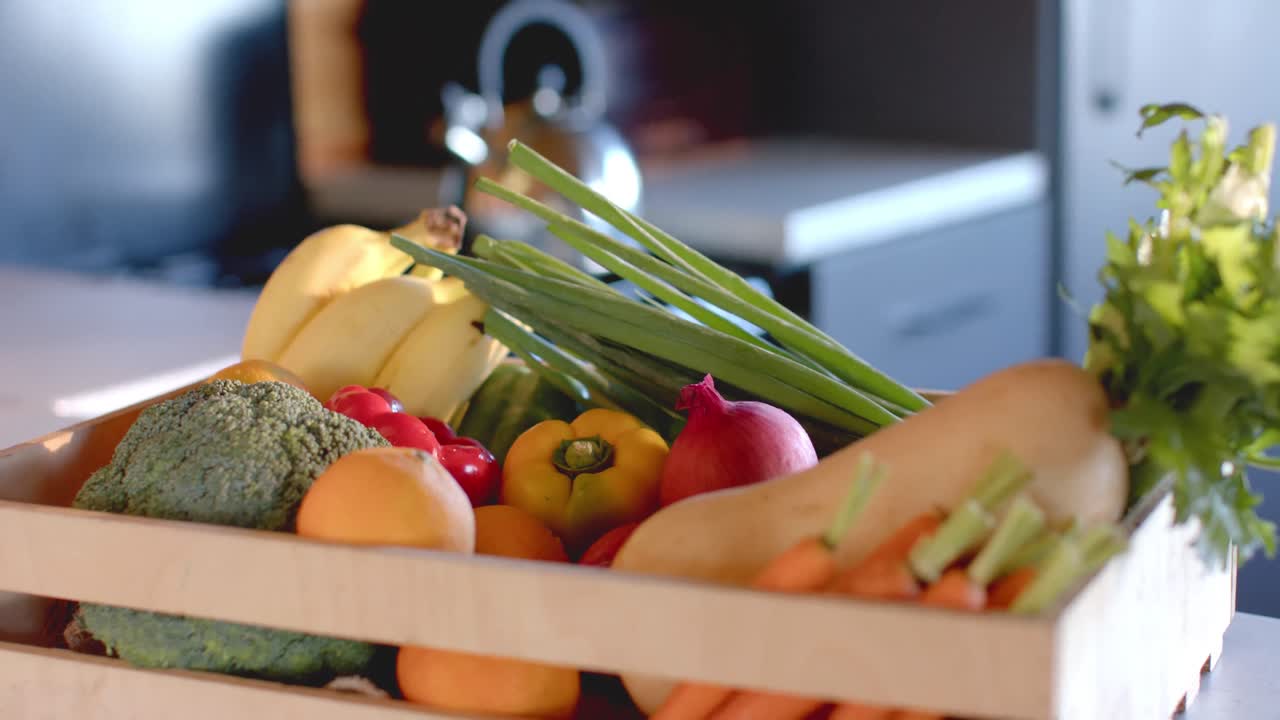 caja de verduras orgánicas en la encimera en una cocina soleada, cámara lenta