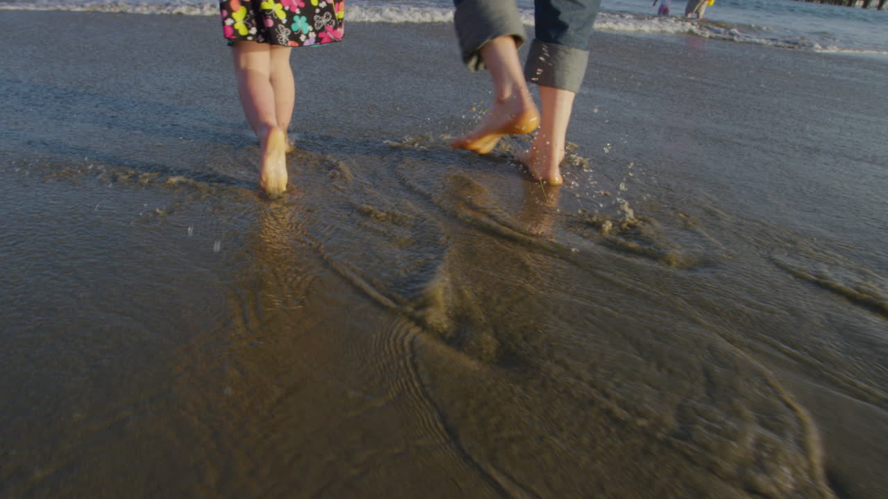 Little girl happily walking on beach with dad in shallow water