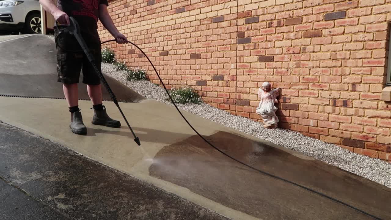 Man wearing boot power washing concrete