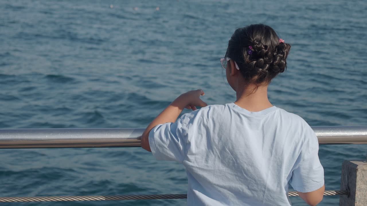 Girl looking at the sea from the pier