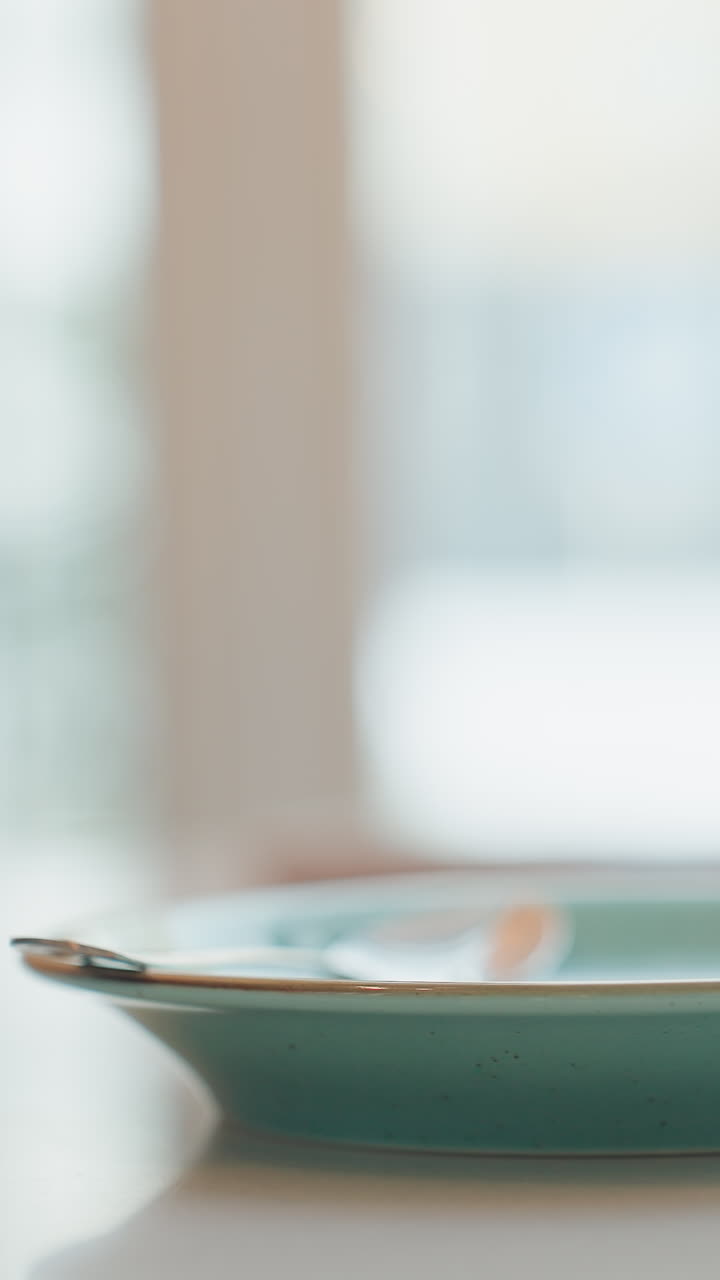 caucasian hands gripping turquoise cup on saucer intimate closeup of morning ritual. Barista studying new recipe, parent calming child, office worker taking brief coffee break. Soft bokeh windowlight