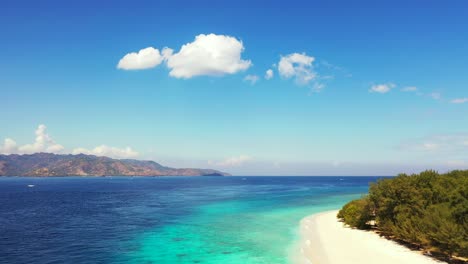 paradise exotic beach with white sand washed by tranquil blue turquoise sea under a bright blue sky with overhanging white clouds in bali